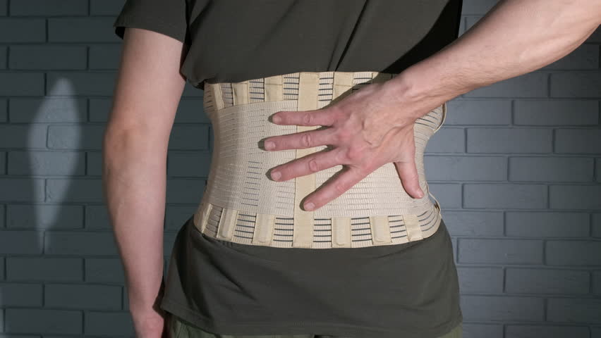Feel back pain in corset. A man feeling back pain and wearing the medical corset