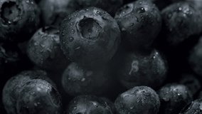 Macro shot of fresh blueberries covered in water droplets. Close-up view emphasizes the texture and moistness of the berries, set against a dark background. Fresh Blueberries with Water Droplets - Powered by Shutterstock - Get 15% off with code: PIKWIZARD15