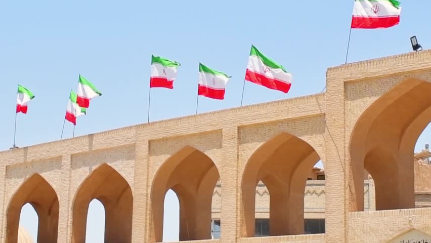 Many iranian flags wave in wind on rooftop of building