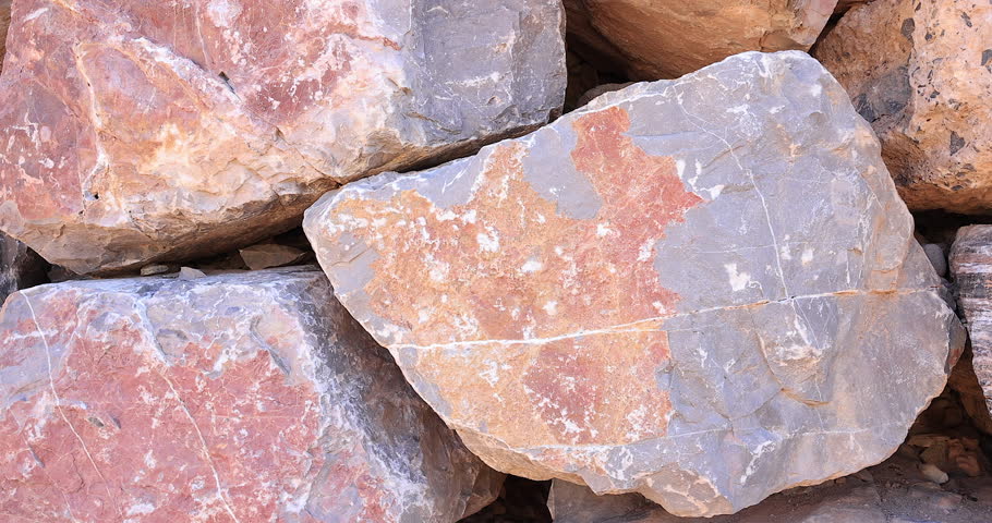 Closeup small gray and rust color with white mineral streaks and cracks in colorful dry stack wall of worn stones 4k