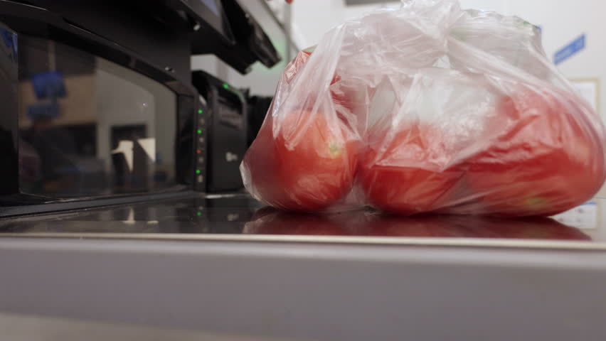 Man Puts Groceries Into Bags at Self-checkout Counter in Store. Shopping for Groceries at Supermarket. Man operates Self-service Checkout, Scanning His Items and Placing Them in Bags. 