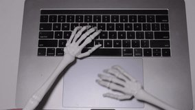 Mystical skeleton hands type away on a laptop during a spooky Halloween night - Powered by Shutterstock - Get 15% off with code: PIKWIZARD15