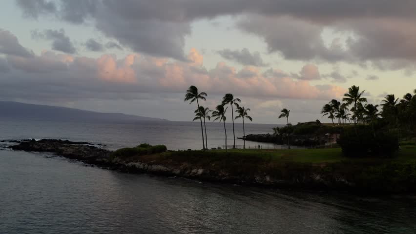 Epic sunrise clouds behind palm trees in Kapalua Bay, Maui, Hawaii