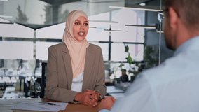 Muslim woman working together with colleague as team of professional bank specialists people. Young businesswoman in hijab making financial consultation for client, business partner at desk in office - Powered by Shutterstock - Get 15% off with code: PIKWIZARD15