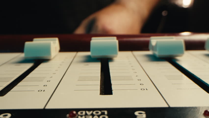 Music studio close up, Close up hands shot of sound engineer using mixing console, remote control for adjusting sound, audio mixer. Musician creates music, makes remix for DJ set. Sound recording