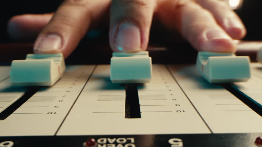 Music studio close up, Close up hands shot of sound engineer using mixing console, remote control for adjusting sound, audio mixer. Musician creates music, makes remix for DJ set. Sound recording