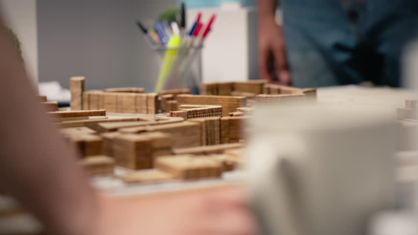 Close up of contractors arranging layout for a housing master plan, simulating site preparation with architectural 3D models before the construction. City planning and redevelopment. Camera B.