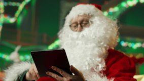 Smiling man dressed as Santa Claus bringing joy to others during holiday season, posting online on tablet. Santa Claus using device to spread sense of wonder during Christmas, camera A close up - Powered by Shutterstock - Get 15% off with code: PIKWIZARD15