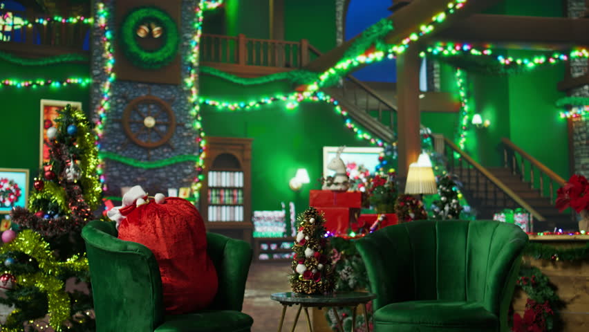 Small Christmas tree on coffee table in room with presents, stockings, fireplace and other holiday props. Empty workshop where Santa Claus receives letters from kids, panning shot