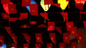 A canopy of small Vietnamese flags and colorful lanterns hangs across a street at night in Hoi An, celebrating national pride and local festive spirit. - Powered by Shutterstock - Get 15% off with code: PIKWIZARD15