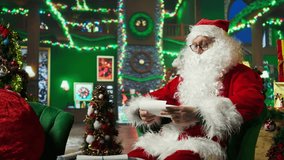 Smiling Santa Claus reading letters from kids, answering them, helping keep belief alive, showing thumbs up sign. Elderly person wearing Christmas costume doing positive agreement gesturing, camera A - Powered by Shutterstock - Get 15% off with code: PIKWIZARD15