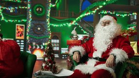 Santa Claus reading kids letters using augmented reality tech after adorning workshop with Christmas ornaments. Santa in holiday season ambiance reading children wish lists on AR hologram, camera A - Powered by Shutterstock - Get 15% off with code: PIKWIZARD15