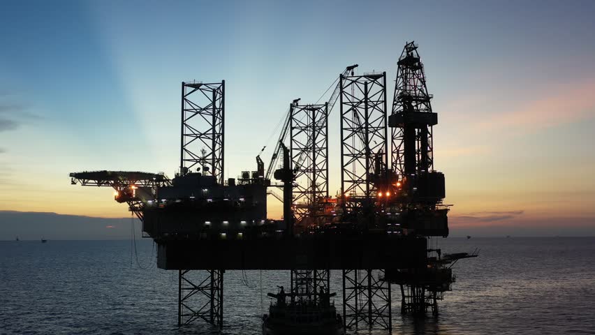 Aerial top view of offshore jack up rig and offshore platform during sunset for oil and gas exploration and production. 