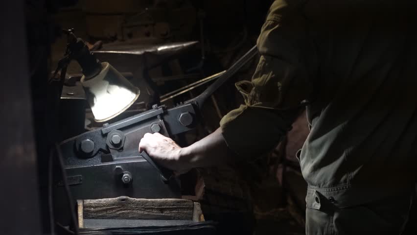 A craftsman uses a hand shear to cut the material into the shape of a knife
