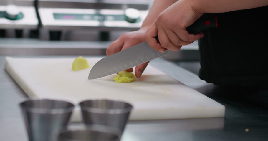 Dicing potato. Chopping vegetable. Chef mincing by sharp knife on kitchen board ingredient. Professional restaurant technique service.