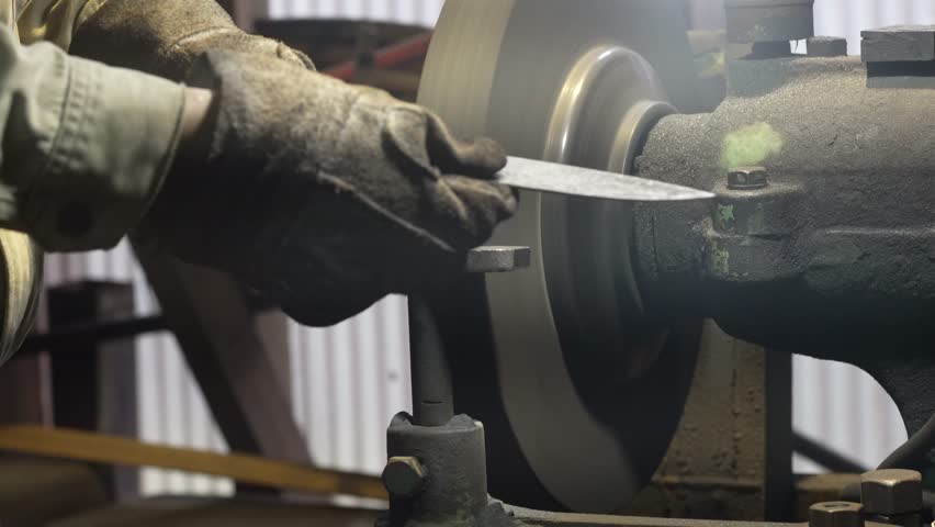 A craftsman shaping the metal using a grinder