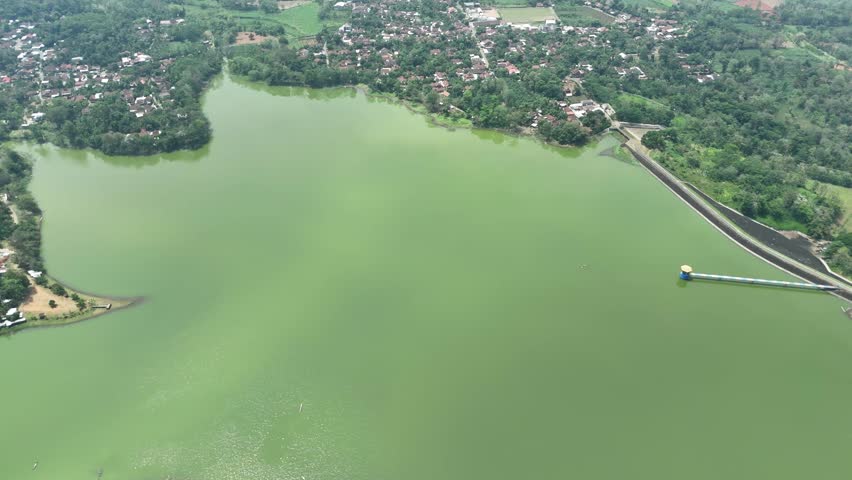 Panoramic Aerial View of Serene Green Lake Surrounded by Lush Village Scenery