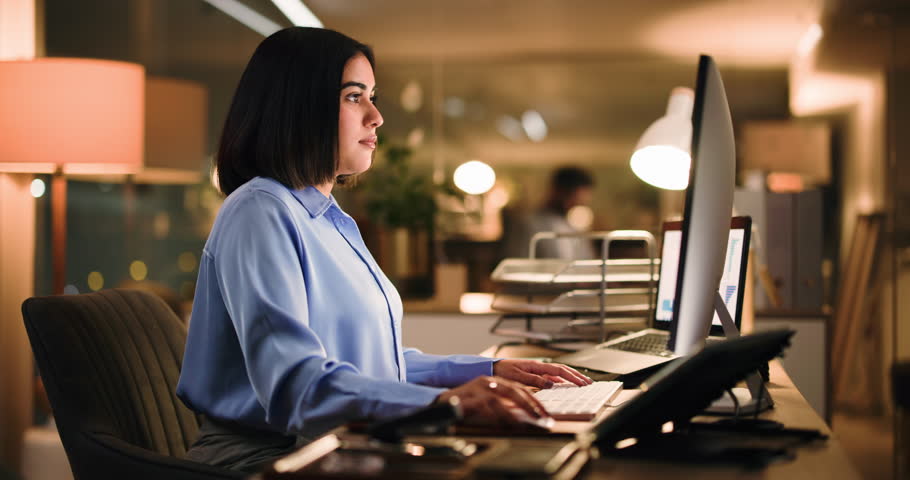 Woman, typing and computer at startup, night and review stats for web traffic at media company. Person, website manager and pc with feedback, graphs and deadline for analytics at creative agency