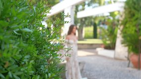 Bride in wedding dress walking outdoors with green leaves foreground - Powered by Shutterstock - Get 15% off with code: PIKWIZARD15