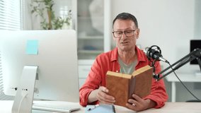 Professional content creator reading book while recording podcast, sitting at home studio desk with microphone and computer - Powered by Shutterstock - Get 15% off with code: PIKWIZARD15