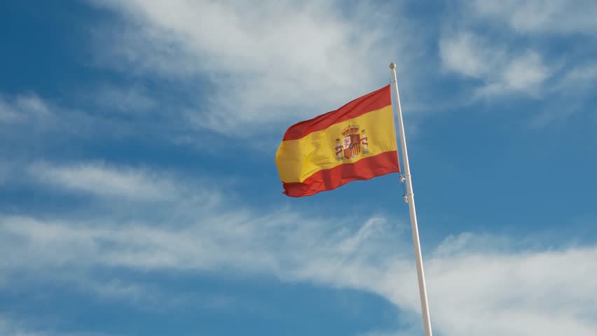 Spanish flag waving gracefully against a bright blue sky. A powerful symbol of national pride, unity, and heritage, capturing the essence of Spains cultural identity