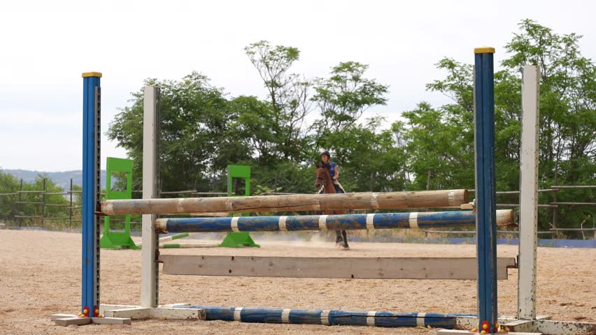 Horse riders training by jumping over obstacles at an equestrian center