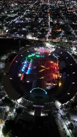 Aerial top down of flashing lights of music show in open air stadium of Santo Domingo. Vertical shot. Lighting cityscape and streets of capital in Dominican republic. Concert of barbarella.