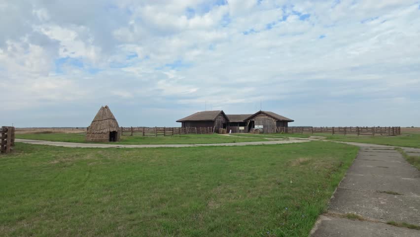 Traditional thatched barn with corral on the endless Hortobágy plain on a calm cloudy day in Hungary.