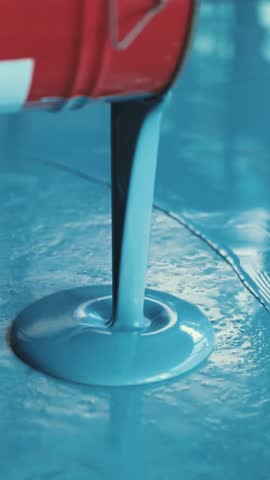 Blue epoxy resin is poured on a floor by a worker