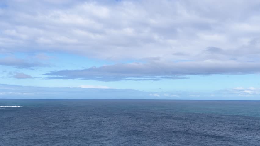 Camera pans across rugged coastal cliffs, blue ocean, and dramatic sky at Cape Schanck, Australia