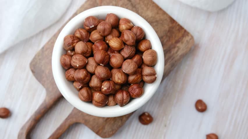 Bowl of whole hazelnuts on wooden board