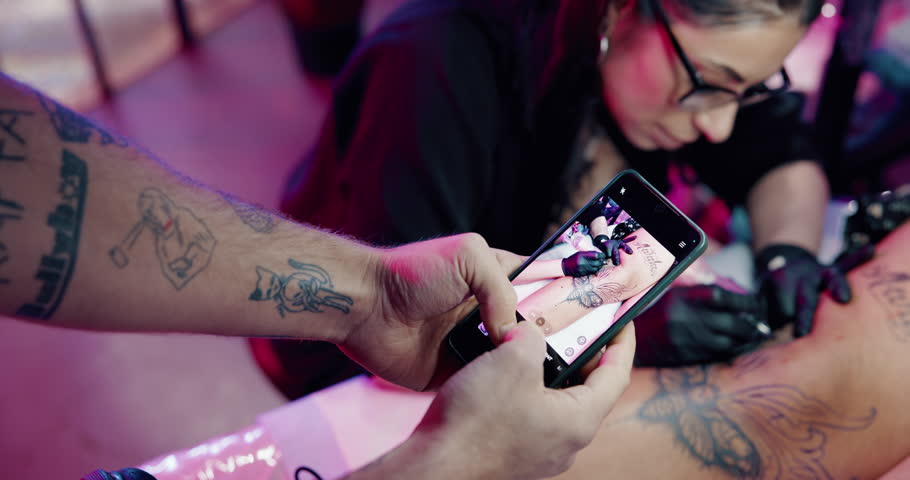 Hands, photography and phone screen with tattoo in studio for leg art, design and social media post. Small business, client and permanent body ink in parlor for aesthetic, creative process and artist