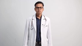 Portrait of relieved determined Asian doctor male meditates with closed eyes, practices breathing exercise or yoga to calm down, stands in lotus pose, poses over white background, makes zen gesture - Powered by Shutterstock - Get 15% off with code: PIKWIZARD15