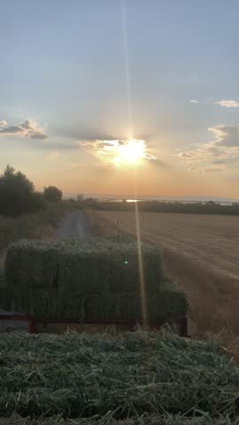 Hay Bale Trailer on a Rural Dirt Road at Sunset