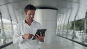 Portrait of businessman scrolls internet on digital tablet in office lobby. Mature entrepreneur in white shirt checks market trends online with mobile device in business center - Powered by Shutterstock - Get 15% off with code: PIKWIZARD15