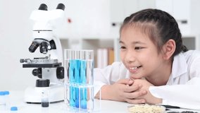 Young primary school student girl in white lab coat holding test tube with blue liquid, smiling and engaging in scientific activity, with laboratory equipment, educational science class back to school - Powered by Shutterstock - Get 15% off with code: PIKWIZARD15