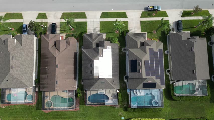 A dynamic aerial shot zooming upward and spinning above residential homes in Kissimmee, Orlando. Captures suburban layout, rooftops, and peaceful neighborhood under Florida skies.