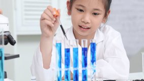 A young girl uses dropper to add liquid into test tubes during a science activity in classroom, representing curiosity, education, back to school, learning, experimentation, and early lab experience. - Powered by Shutterstock - Get 15% off with code: PIKWIZARD15