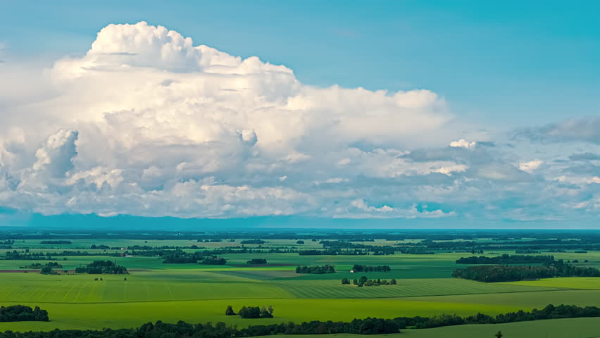 Wide flat rural landscape agricultural land under large white clouds horizon time lapse