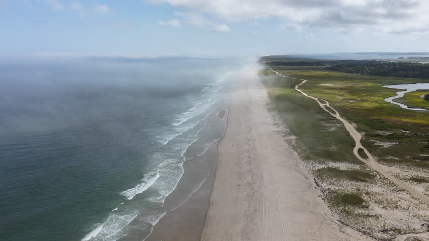 Clouds drift above the scenic Nauset Beach in Orleans, Cape Cod, Massachusetts. This aesthetic public beach is a popular destination for people on vacation during summer months. 