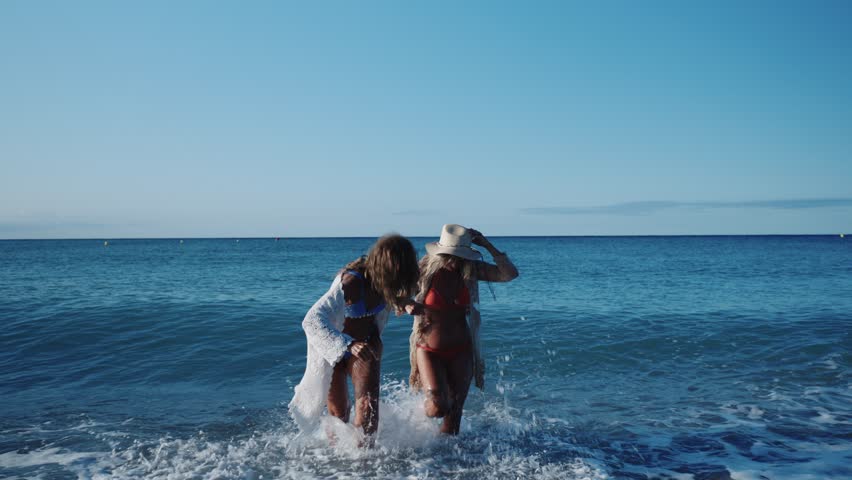 Happy mature women running on the beach in slow motion