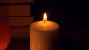 Flickering candlelight creates a warm autumn ambiance, casting soft shadows on books and seasonal decorations, enhancing the cozy fall atmosphere. autumn is coming concept - Powered by Shutterstock - Get 15% off with code: PIKWIZARD15