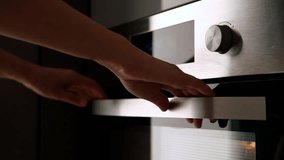 Side view of the woman turning on the electrical oven in the kitchen to baking dessert. Checking readiness of the food - Powered by Shutterstock - Get 15% off with code: PIKWIZARD15