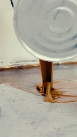 Construction worker pouring brown epoxy resin on a concrete floor
