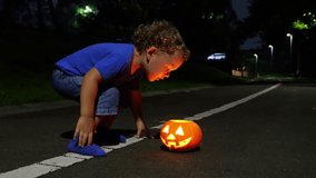 Toddler, determined and focused, blows at glowing candles inside a small pumpkin Jack-o'-lantern on the ground. Despite his efforts, candlelight flickers but remains lit. - Powered by Shutterstock - Get 15% off with code: PIKWIZARD15