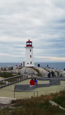 Vertical Video,Rapid Movement Of People Exploring The Iconic Peggys Cove Lighthouse On Atlantic Coast. Time-Lapse Shows Busy Tourist Day On Rugged Granite Rocks With Ocean Views In Nova Scotia, Canada