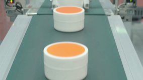 Demo making of Cosmetic cream jars move along automated conveyor belt in modern factory. Industrial production line concept  automation packaging manufacturing and mass production technology. close up - Powered by Shutterstock - Get 15% off with code: PIKWIZARD15