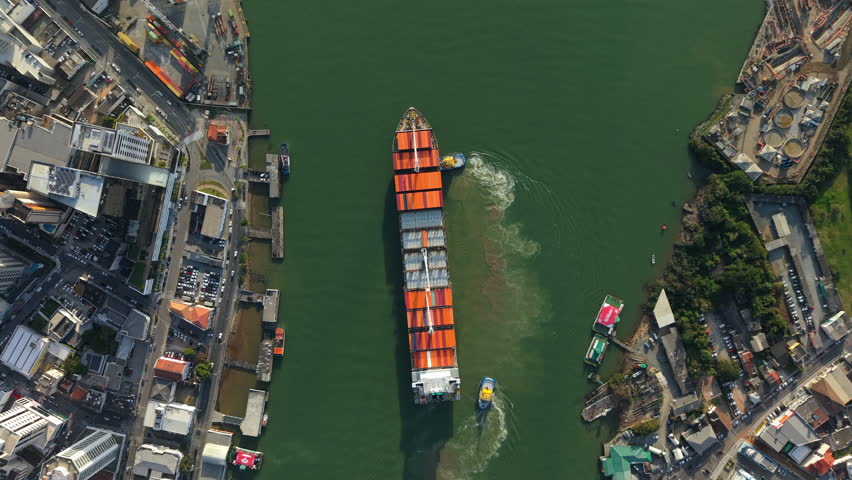 Aerial tops down above colorful Container Ship, transportation cargo in green waters of Itajaí port, Brazil