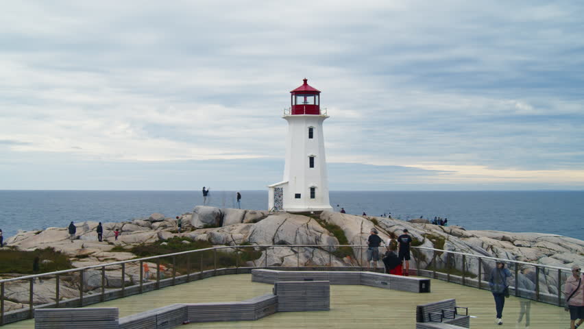 Time-Lapse Rapid Crowd Movement Along Coastal Rocks At Famous Lighthouse. Time-Lapse Shot In Nova Scotia Shows Energy Of A Busy Day By The Sea With Clear Blue Sky And Rugged Shore.