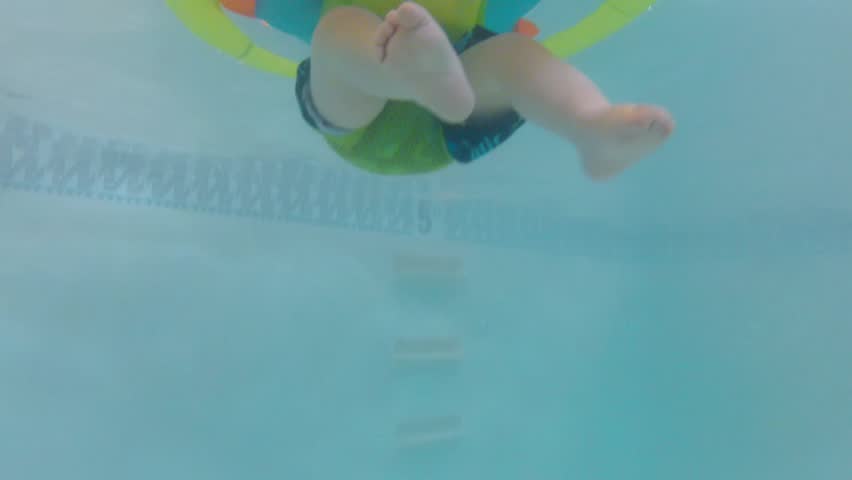 Underwater shot of a cute little baby boy at the swimming pool with his family.